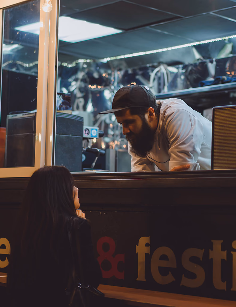 A food vendor speaking with a customer through a service window