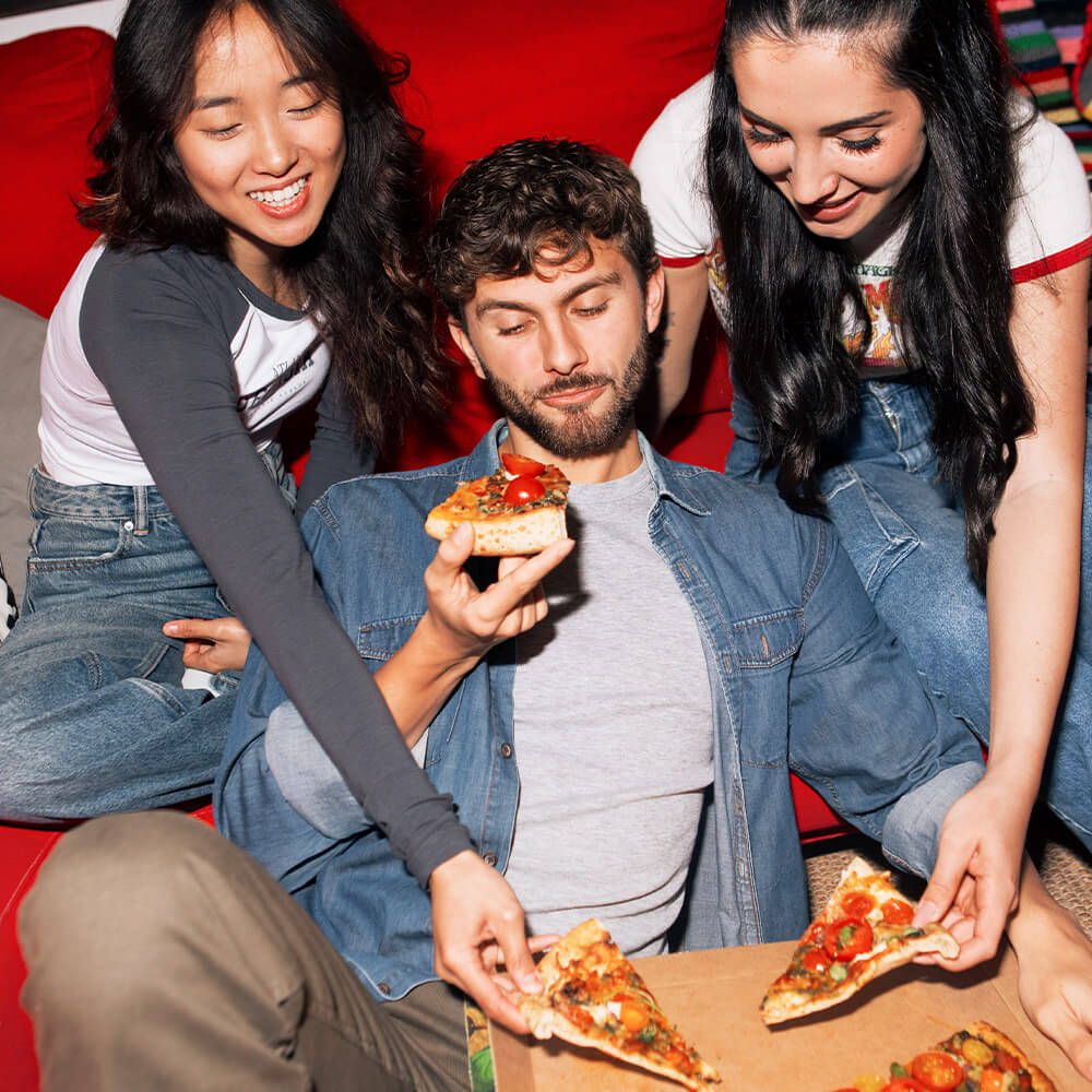 Three friends sharing slices of pizza